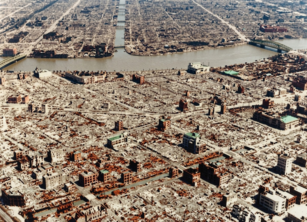 東京大空襲後の、現在の中央区東日本橋付近。隅田川が流れ、焼け野原となった市街地にコンクリート造の建物だけがわずかに残っているカラー化写真。