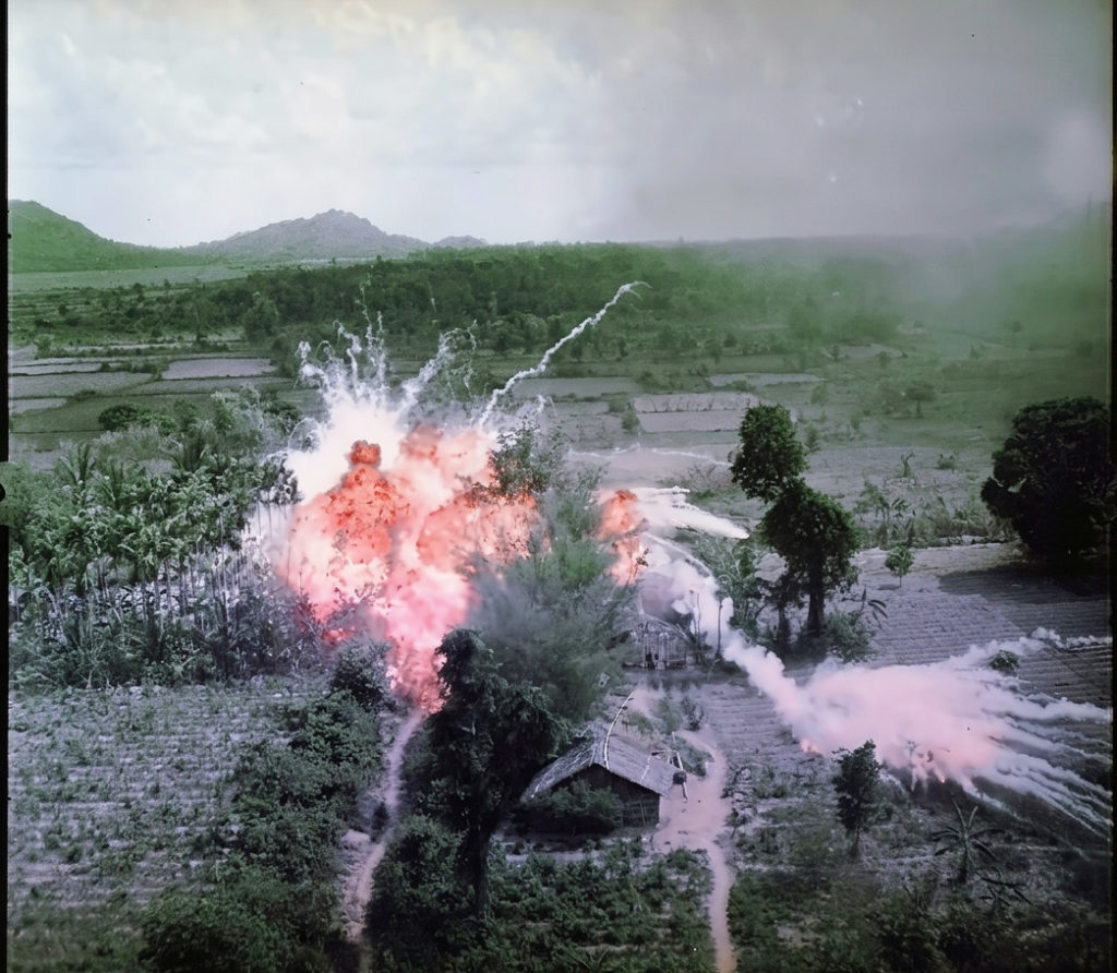 ベトナム戦争時、生い茂るジャングルや民家の近くで激しく燃え上がるナパーム弾の爆発。アメリカ空軍による爆撃の様子を捉えたカラー写真。